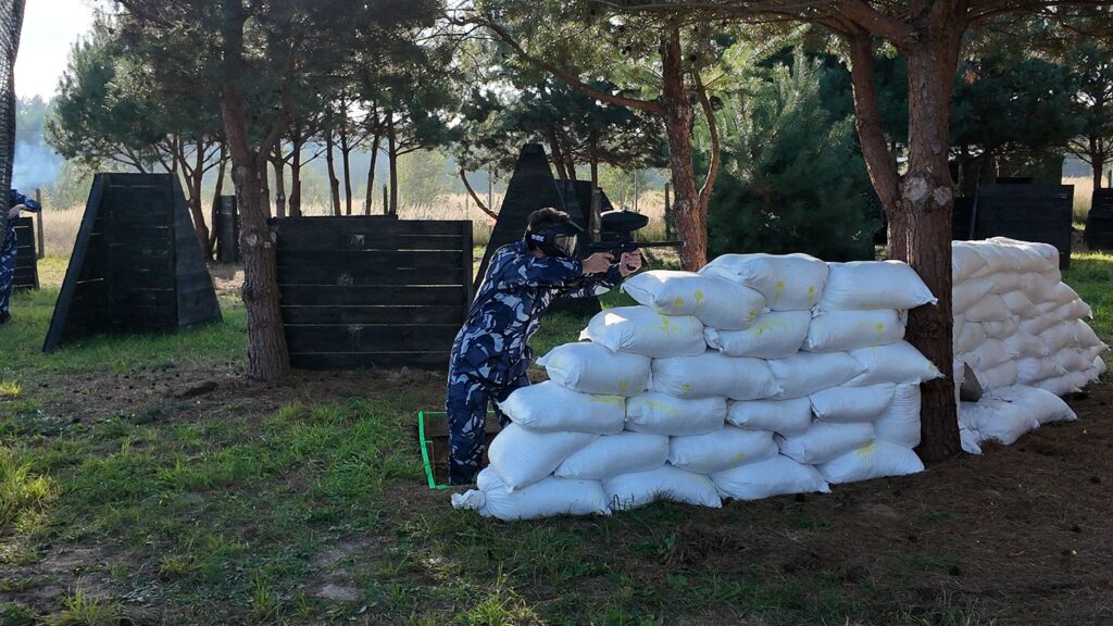 Grupa graczy chowających się za przeszkodami na polu paintballowym Kozbifield w Busku Zdroju